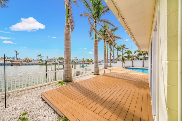 wooden deck featuring a water view, a fenced in pool, fence, and a boat dock