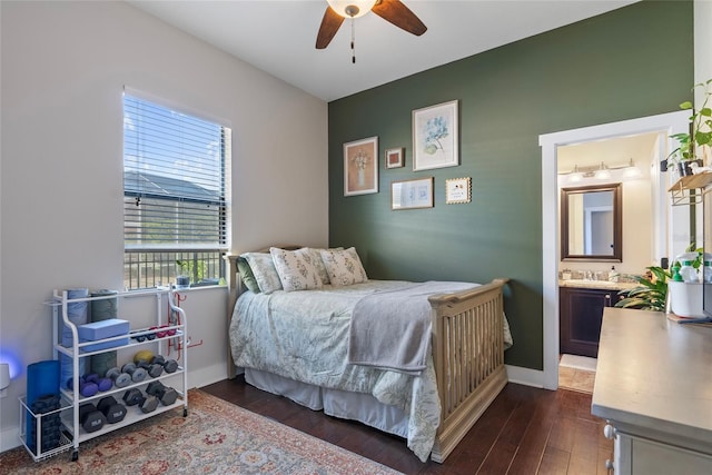 bedroom featuring a ceiling fan, ensuite bath, baseboards, and dark wood-style flooring