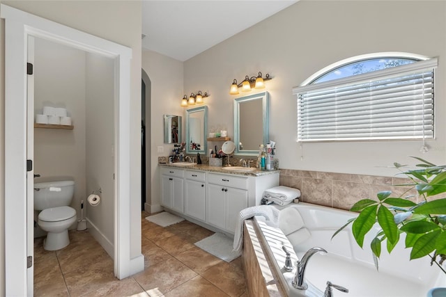 full bath featuring a bath, double vanity, a sink, and toilet