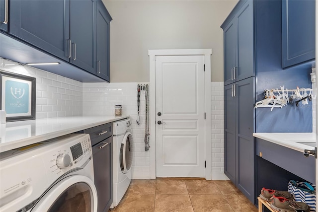 laundry area featuring cabinet space, light tile patterned flooring, tile walls, and washing machine and clothes dryer