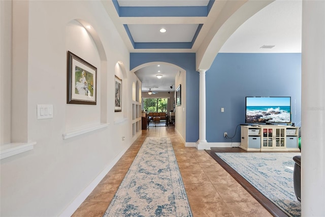 hallway featuring arched walkways, decorative columns, visible vents, baseboards, and tile patterned floors