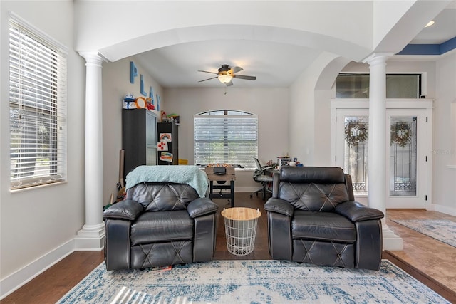 living area with a wealth of natural light, a ceiling fan, decorative columns, and baseboards