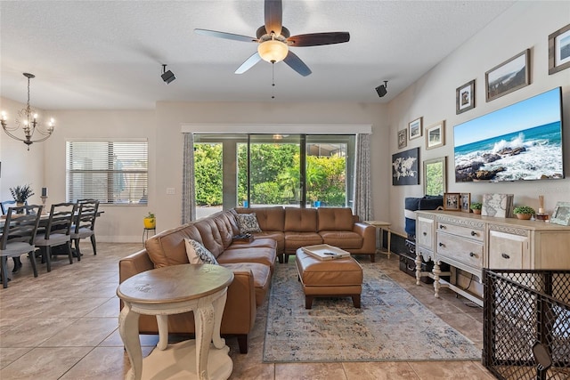 living room featuring a textured ceiling, baseboards, and ceiling fan with notable chandelier