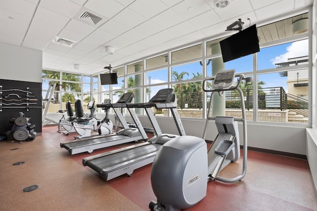 exercise room with baseboards, visible vents, and a paneled ceiling