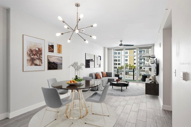 dining room featuring baseboards, ceiling fan with notable chandelier, expansive windows, and light wood-style flooring