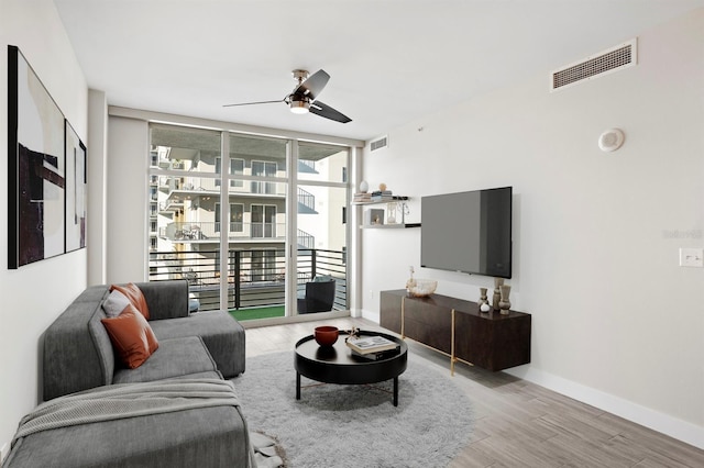 living room featuring visible vents, wood finished floors, a ceiling fan, and expansive windows
