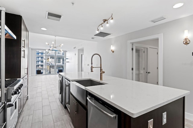 kitchen with visible vents, stainless steel appliances, a center island with sink, and a sink