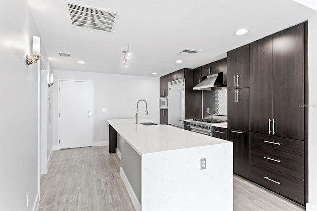 kitchen with visible vents, under cabinet range hood, light countertops, and a sink