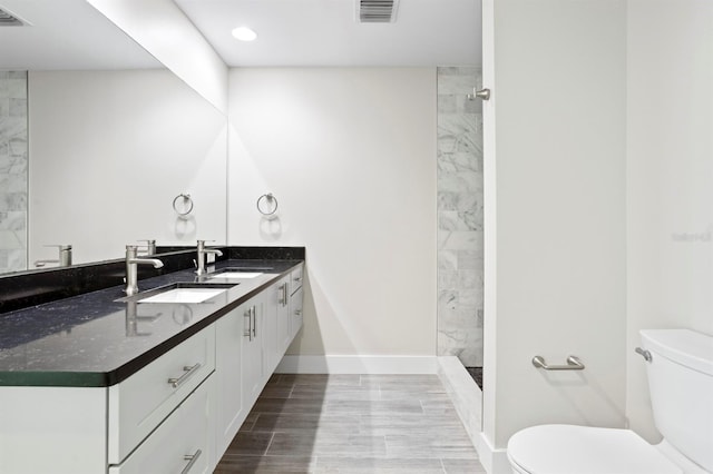 bathroom featuring toilet, visible vents, tiled shower, and vanity