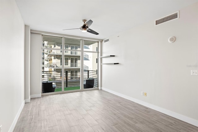 unfurnished living room with wood finished floors, visible vents, a ceiling fan, and expansive windows