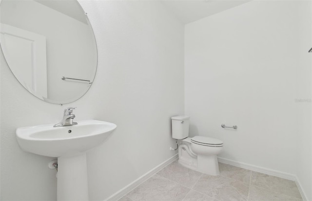 half bath with tile patterned flooring, baseboards, and toilet