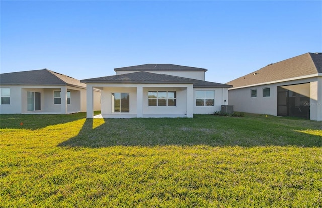 rear view of property with cooling unit, a lawn, and stucco siding