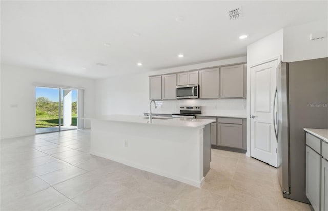 kitchen featuring visible vents, stainless steel appliances, a sink, and gray cabinetry