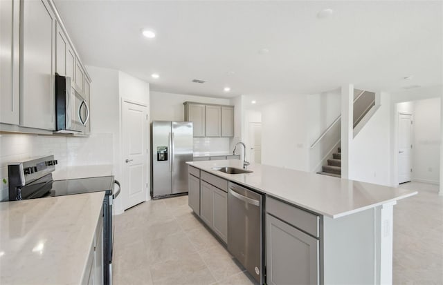 kitchen featuring backsplash, gray cabinets, stainless steel appliances, and a sink