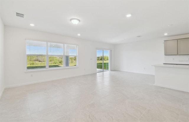 unfurnished living room featuring baseboards, visible vents, and recessed lighting