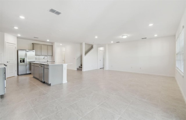 kitchen featuring gray cabinetry, stainless steel appliances, visible vents, open floor plan, and light countertops