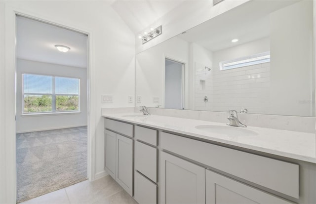 full bath featuring double vanity, tile patterned floors, a sink, and tiled shower