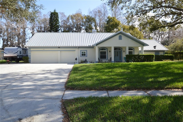 ranch-style home featuring metal roof, a garage, driveway, stucco siding, and a front yard