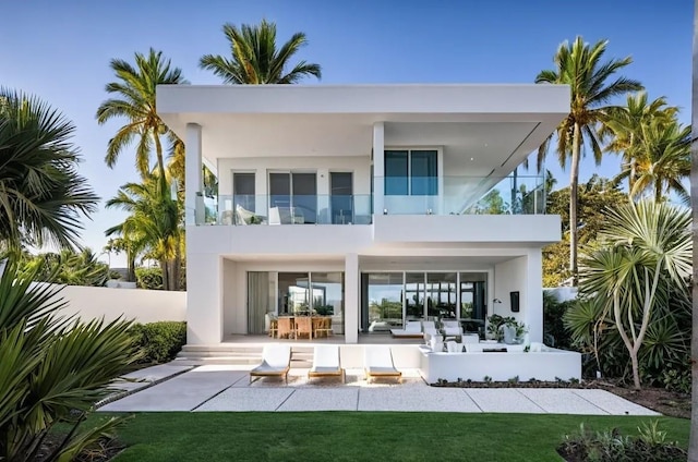 rear view of property with a balcony, stucco siding, fence, and a patio