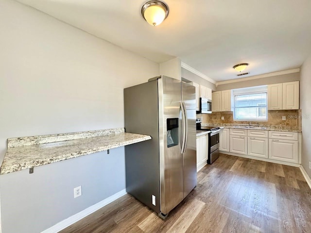 kitchen with stainless steel appliances, white cabinetry, and light stone countertops