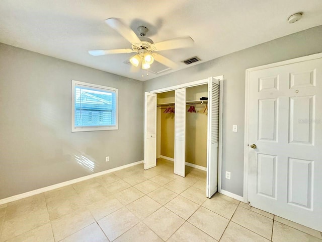 unfurnished bedroom with light tile patterned flooring, ceiling fan, and a closet