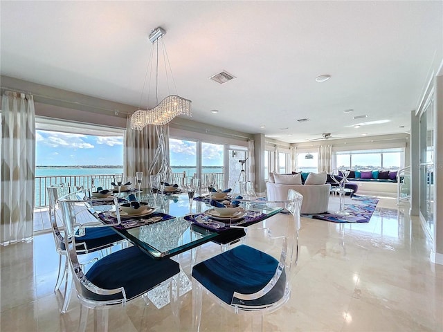 dining room featuring marble finish floor, a water view, ceiling fan, and visible vents