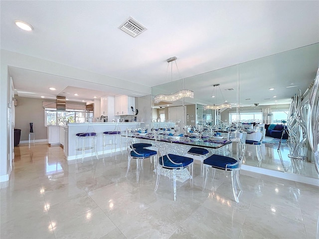 kitchen with visible vents, open floor plan, marble finish floor, a kitchen bar, and pendant lighting