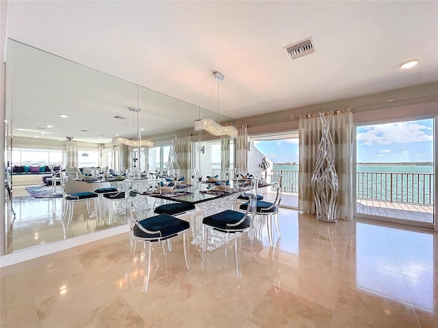 kitchen featuring a wealth of natural light, pendant lighting, a water view, and visible vents