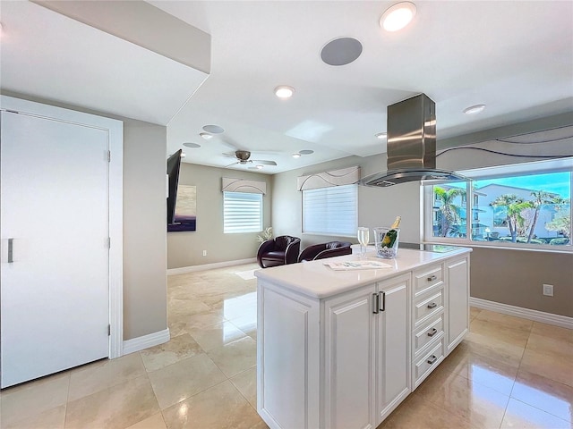 kitchen with a center island, island exhaust hood, light countertops, white cabinetry, and ceiling fan