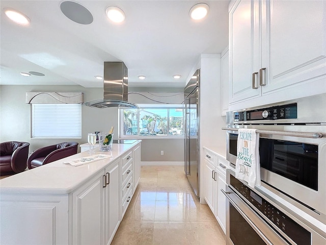 kitchen with double oven, white cabinetry, light countertops, a center island, and island exhaust hood