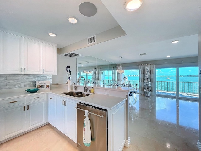 kitchen featuring a peninsula, stainless steel dishwasher, a sink, and white cabinets