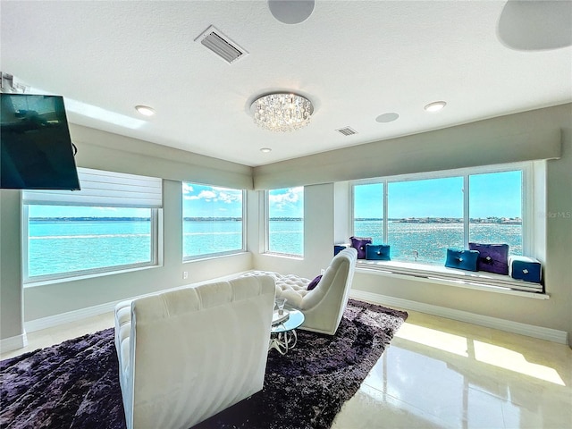 interior space with visible vents, a water view, a wealth of natural light, and baseboards