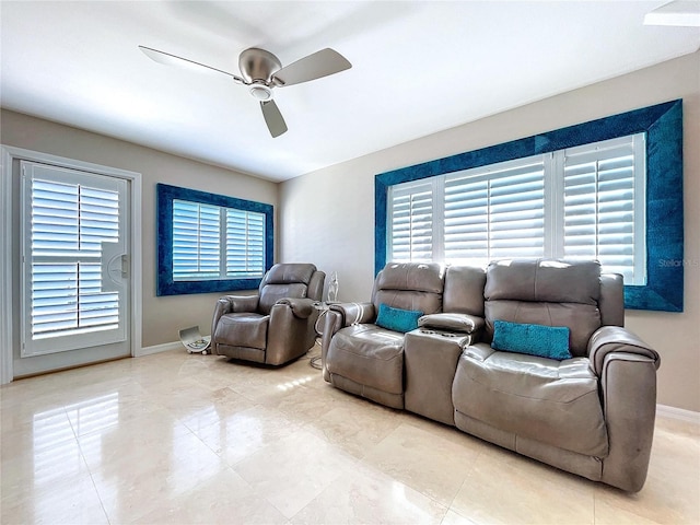 living area with a ceiling fan and baseboards