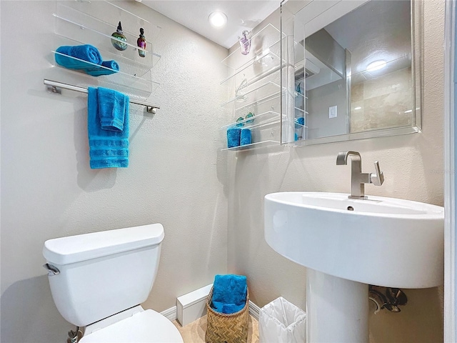 bathroom with a textured wall and toilet