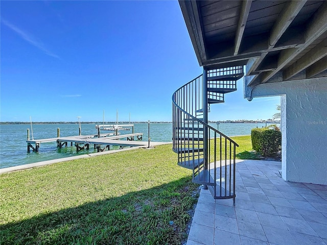 dock area featuring a water view, a lawn, and stairs