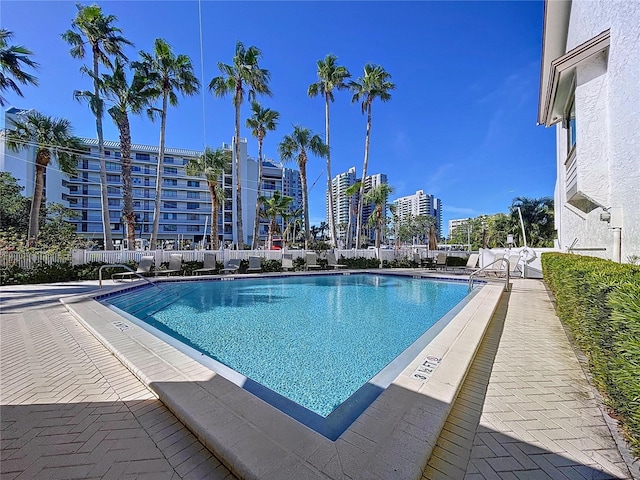 pool featuring a patio, fence, and a city view