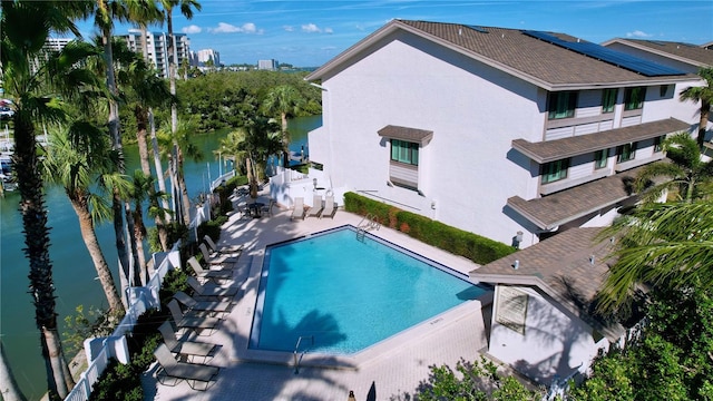 community pool featuring a water view, fence, and a patio