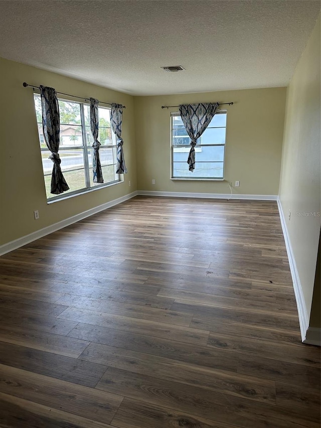 unfurnished room with dark hardwood / wood-style flooring and a textured ceiling