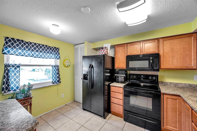 kitchen with light tile patterned floors, black appliances, and a textured ceiling