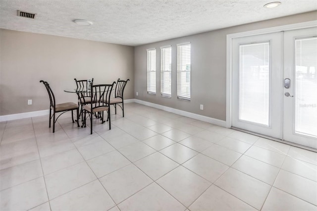 tiled dining room with a textured ceiling and french doors