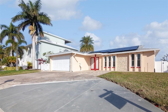 view of front of home featuring a garage, a front lawn, and solar panels