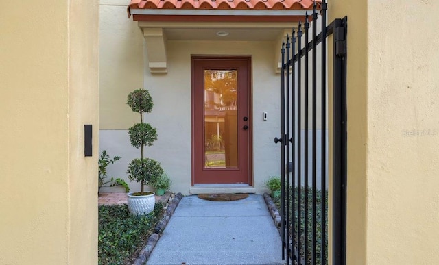 entrance to property with a tile roof and stucco siding