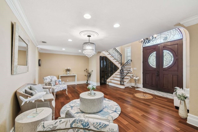 foyer entrance with hardwood / wood-style flooring, crown molding, and a notable chandelier