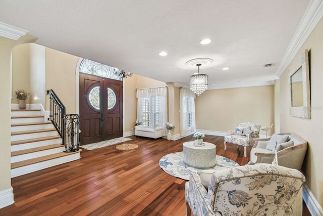 entryway with hardwood / wood-style flooring, ornamental molding, and an inviting chandelier