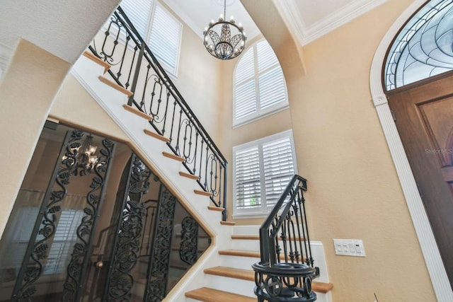 foyer entrance featuring ornamental molding, a chandelier, and a high ceiling