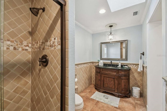 bathroom with tile patterned floors, toilet, crown molding, tile walls, and vanity