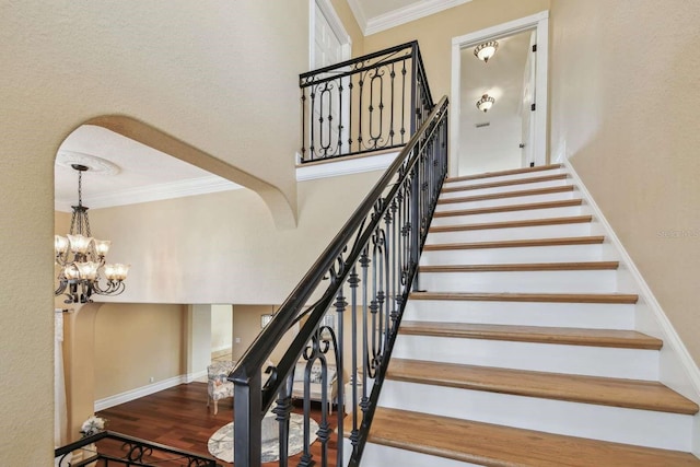 stairway featuring ornamental molding, a chandelier, wood-type flooring, and a high ceiling