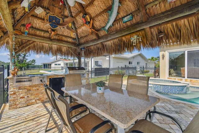 wooden deck featuring a gazebo, a bar, ceiling fan, a grill, and exterior kitchen