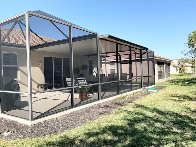 rear view of property with a yard, glass enclosure, and a patio area