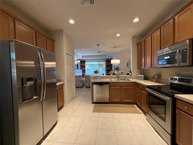 kitchen featuring sink, decorative light fixtures, light tile patterned floors, kitchen peninsula, and stainless steel appliances